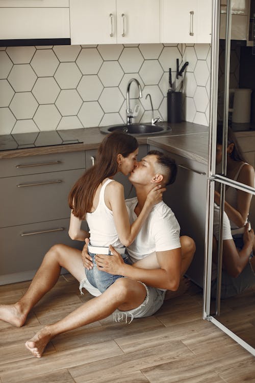Man and Woman Sitting on the Floor While Kissing
