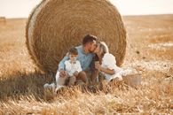 Man and Woman Sitting on Brown Hay Roll