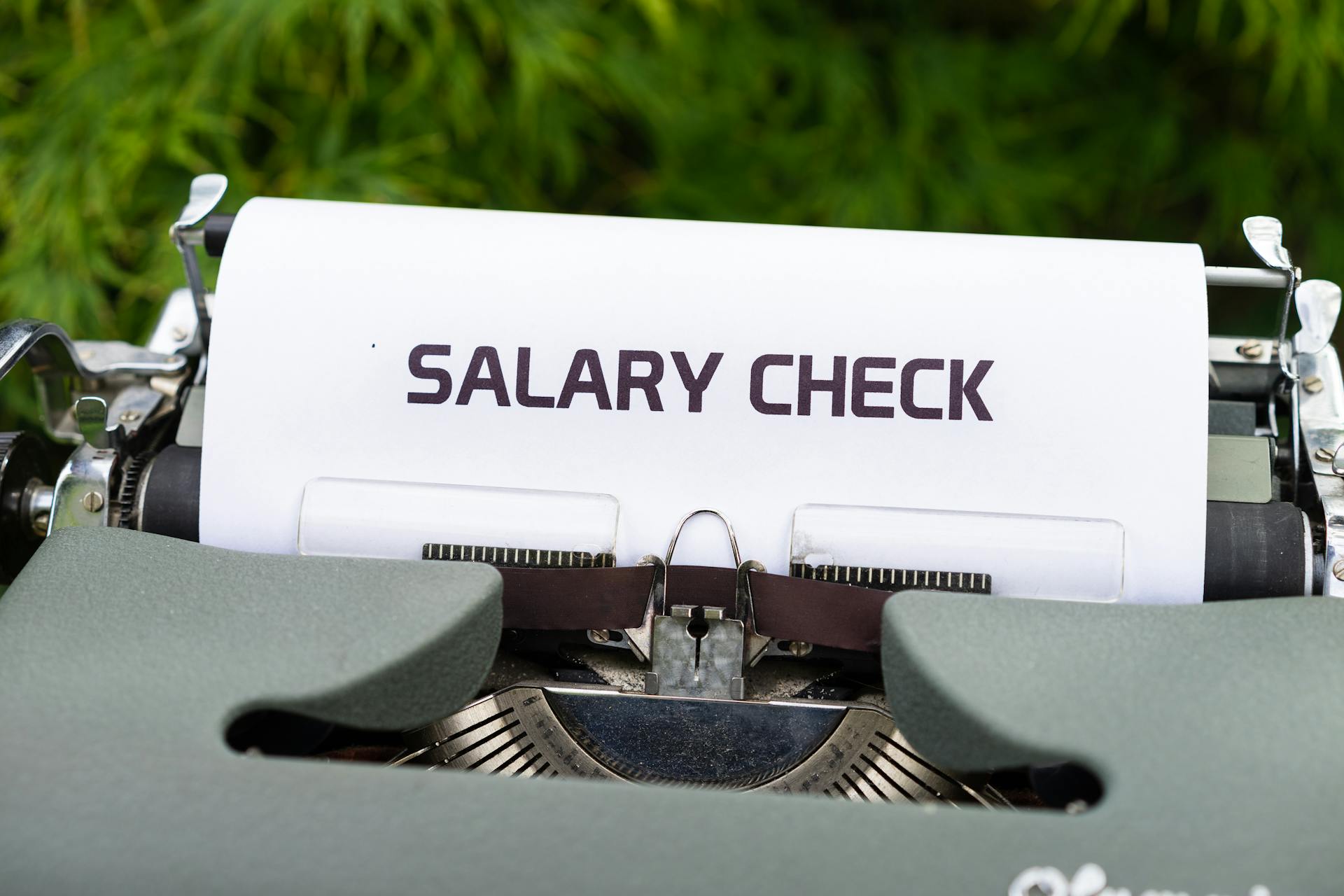 Close-up of a vintage typewriter typing 'Salary Check' on paper, symbolizing payroll and finance.