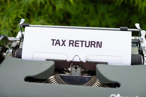 Free Close-up of a vintage typewriter typing 'Tax Return' on paper outdoors. Stock Photo