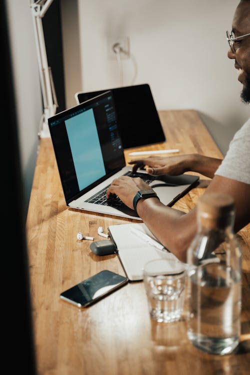 Person Using Macbook Pro On Brown Wooden Table