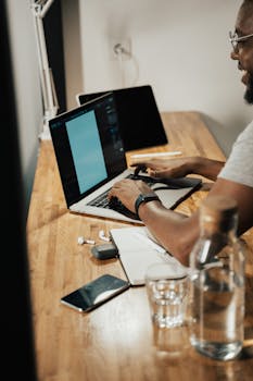 Adult man working on a laptop at home office with a modern setup.