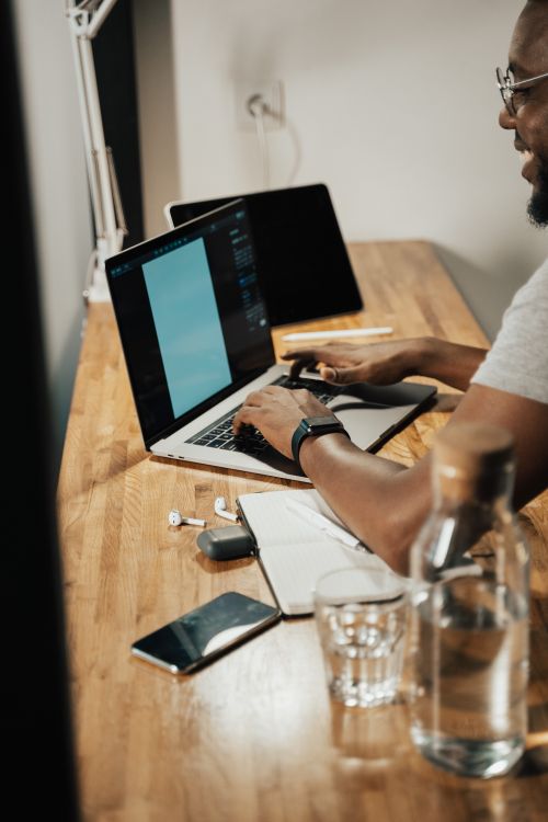 Free Adult man working on a laptop at home office with a modern setup. Stock Photo