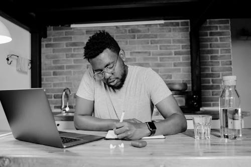 Grayscale Photo of Man Writing 