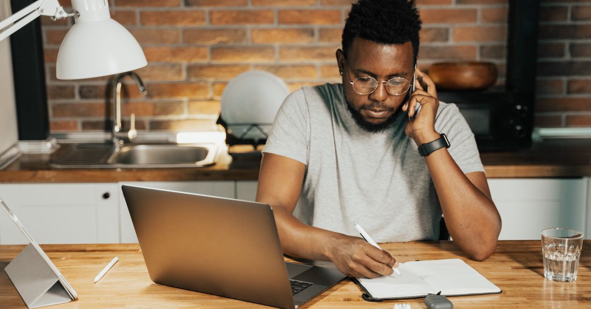 person writing on laptop at kitchen table