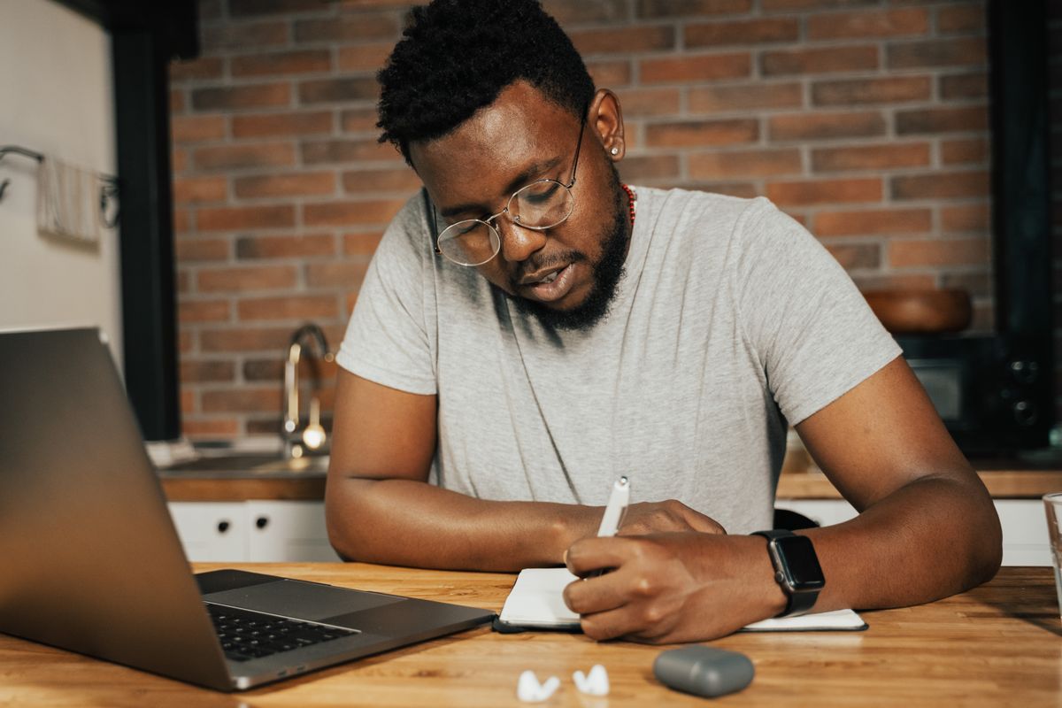 Man in gray crew neck t-shirt writing on paper