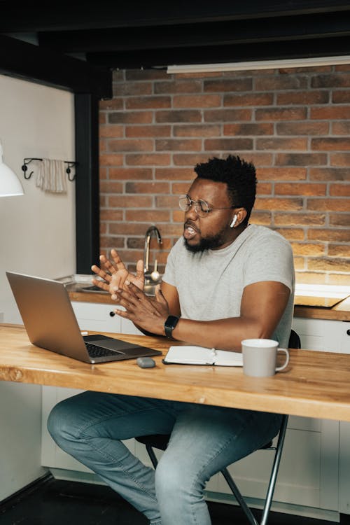 Free African American man engaged in remote work on a laptop at a home office setting. Stock Photo Free African American man engaged in remote work on a laptop at a home office setting. Stock Photo