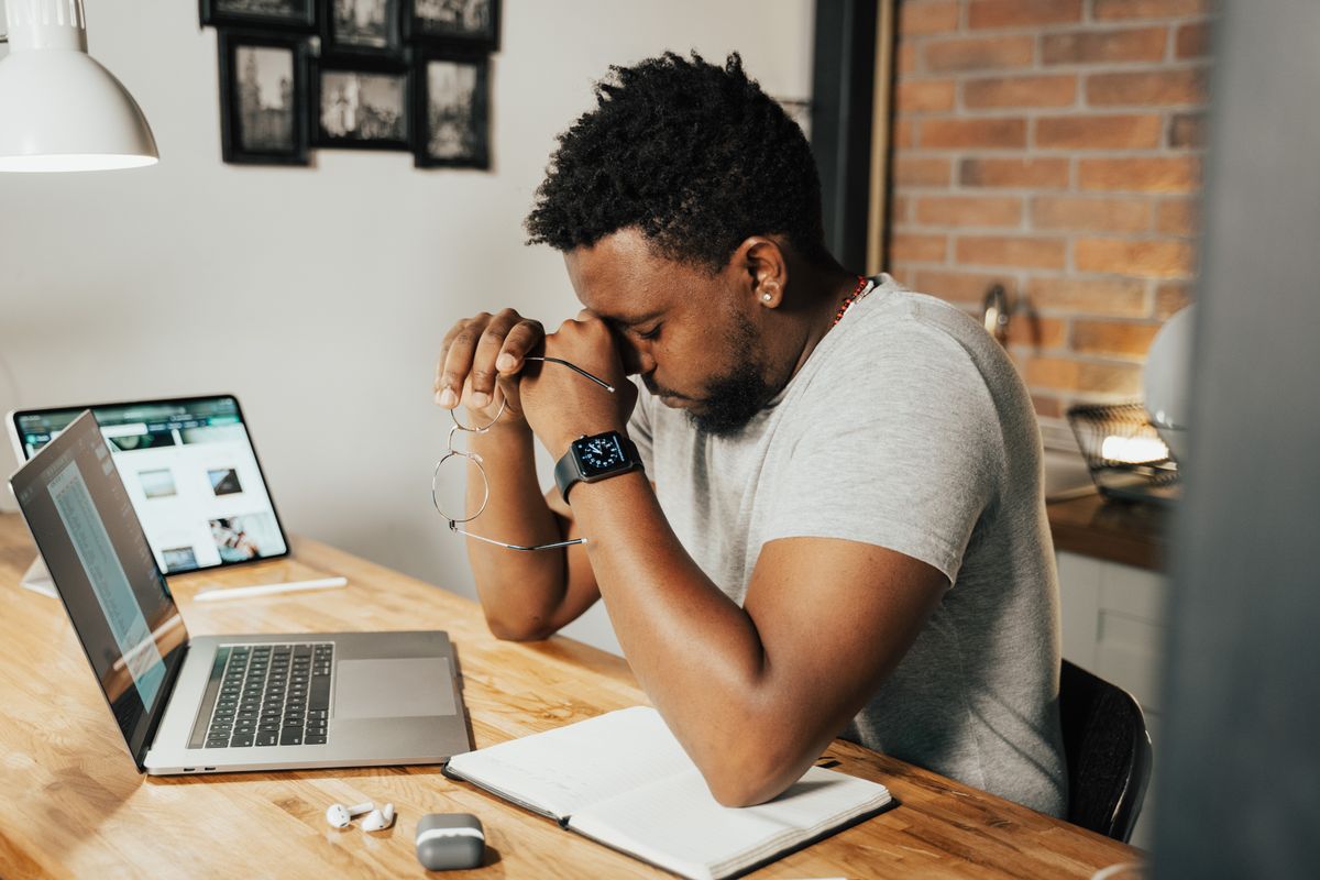 Tired media buyer rubbing his eyes in front of a laptop showing declining ad results