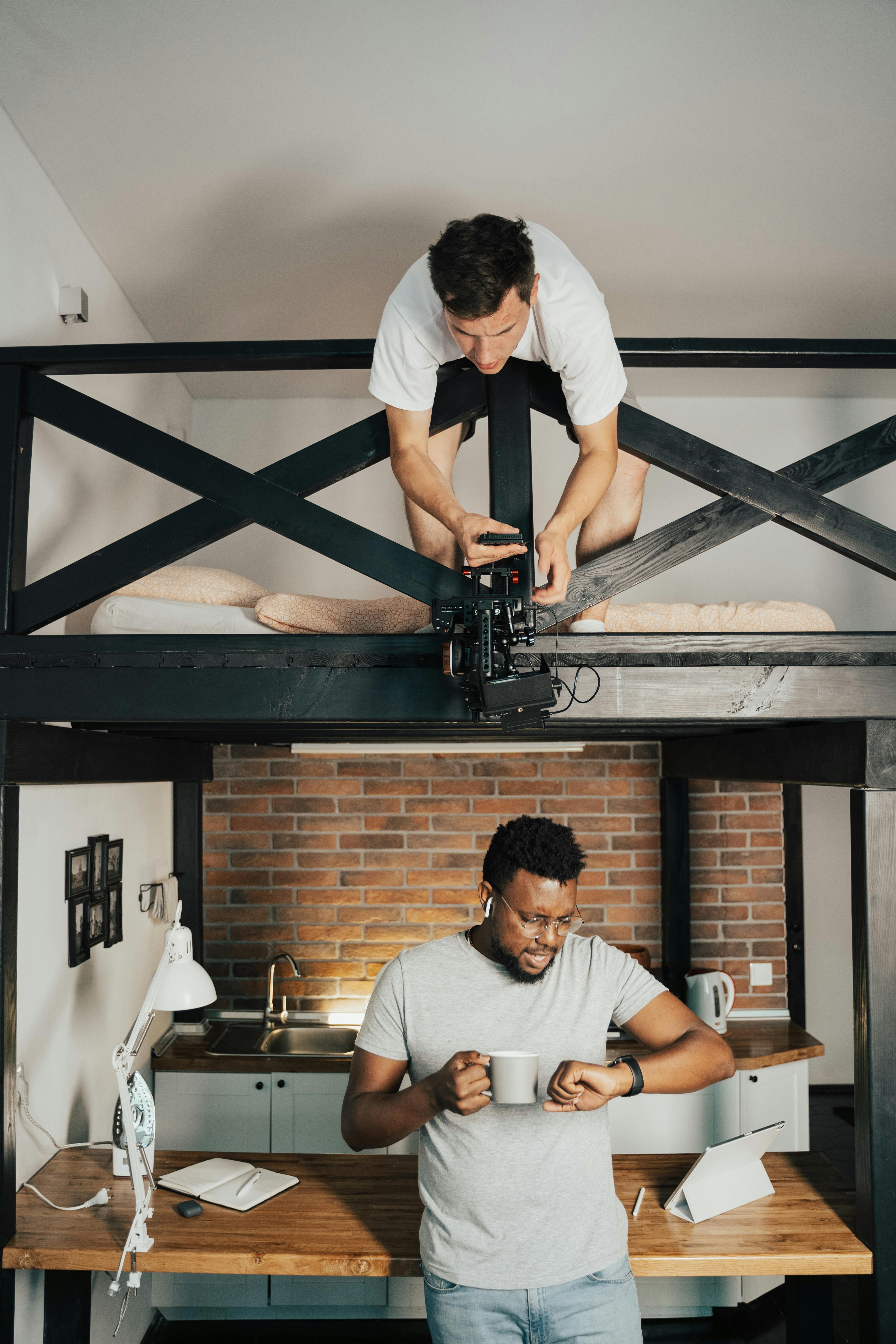 在一个时尚的阁楼厨房里，一个男人拿着马克杯，摄影师正在调整相机