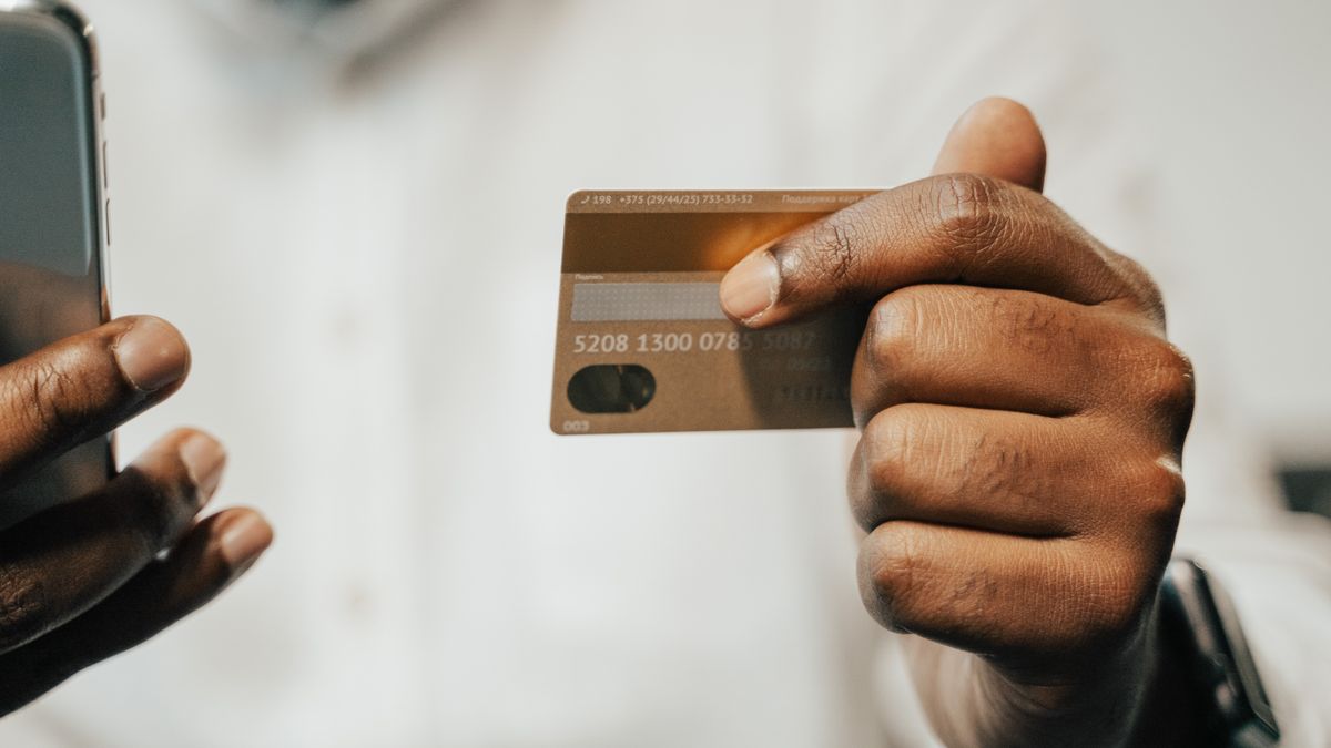 A person holding a smartphone and a credit card while booking online