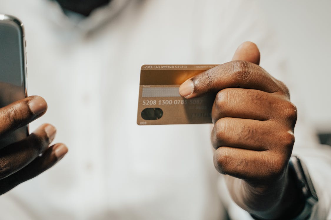 Free Person Holding Brown Credit Card and Cellphone Stock Photo