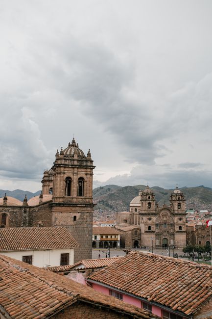 Panoramic view of Cusco skyline featuring the Church of the Society of Jesus against a cloudy sky.