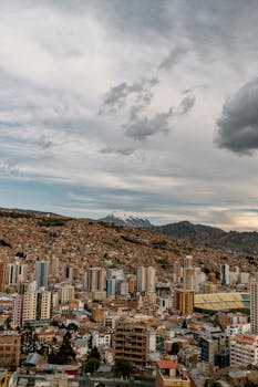 Explore the stunning aerial view of La Paz with its vibrant cityscape set against majestic mountains under a cloudy sky.