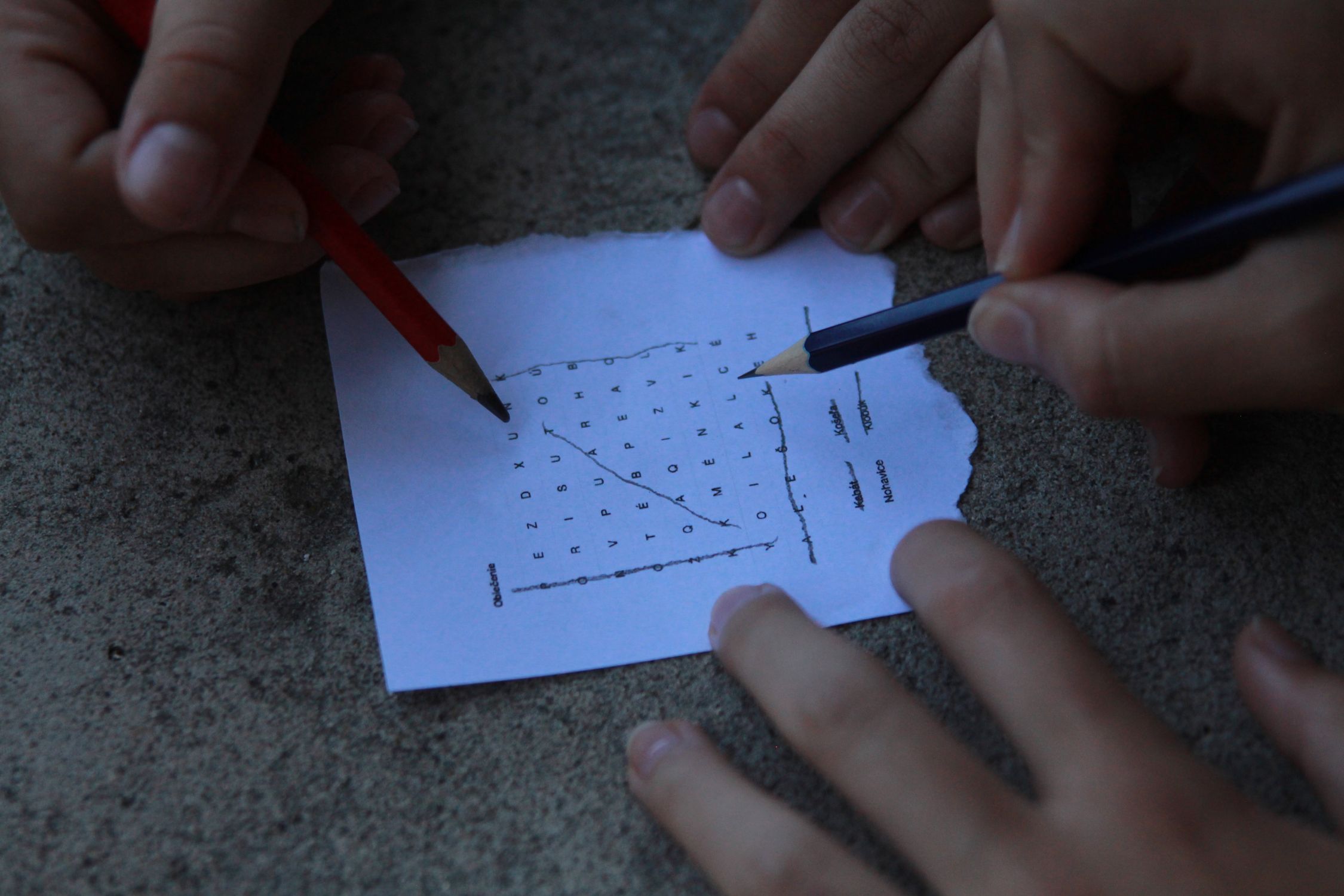People solving a word puzzle with pencils