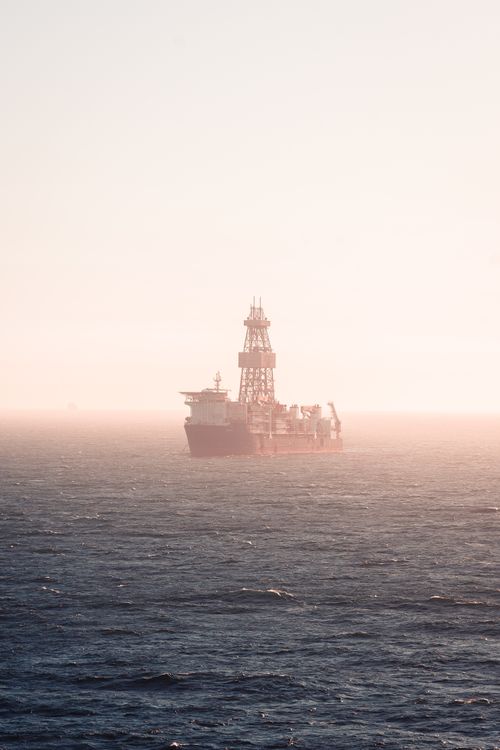 Free A lone cargo ship glides across the foggy Atlantic Ocean under a pale sky, creating a serene and peaceful scene. Stock Photo
