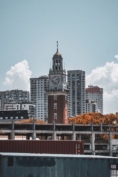 Vertical view of Torre Monumental against Buenos Aires skyline with clouds in the background.