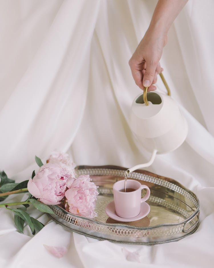 A Hand Pouring Hot Water On Pink Cup