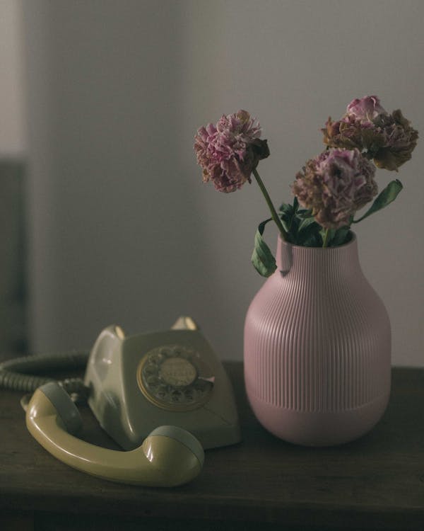 A Dial Telephone beside a Vase of Flowers