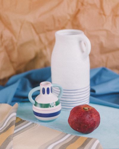 Ceramic jug styled with fabric and a pomegranate — photo by Tamara Velazquez on Pexels
