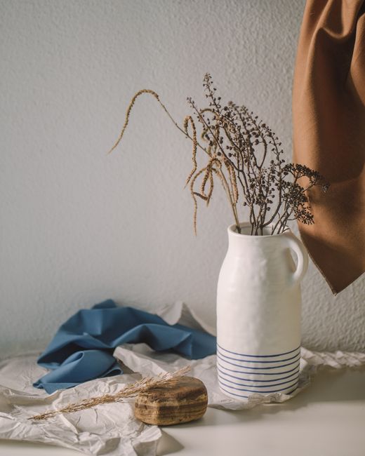 Elegant still life featuring a ceramic vase with dried flowers, capturing a minimalist rustic style.