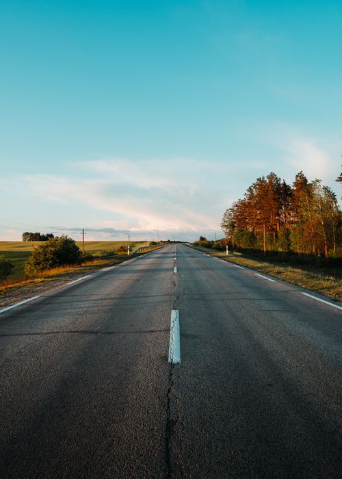 Free Scenic view of a peaceful country road under a clear blue sky in Lithuania. Stock Photo