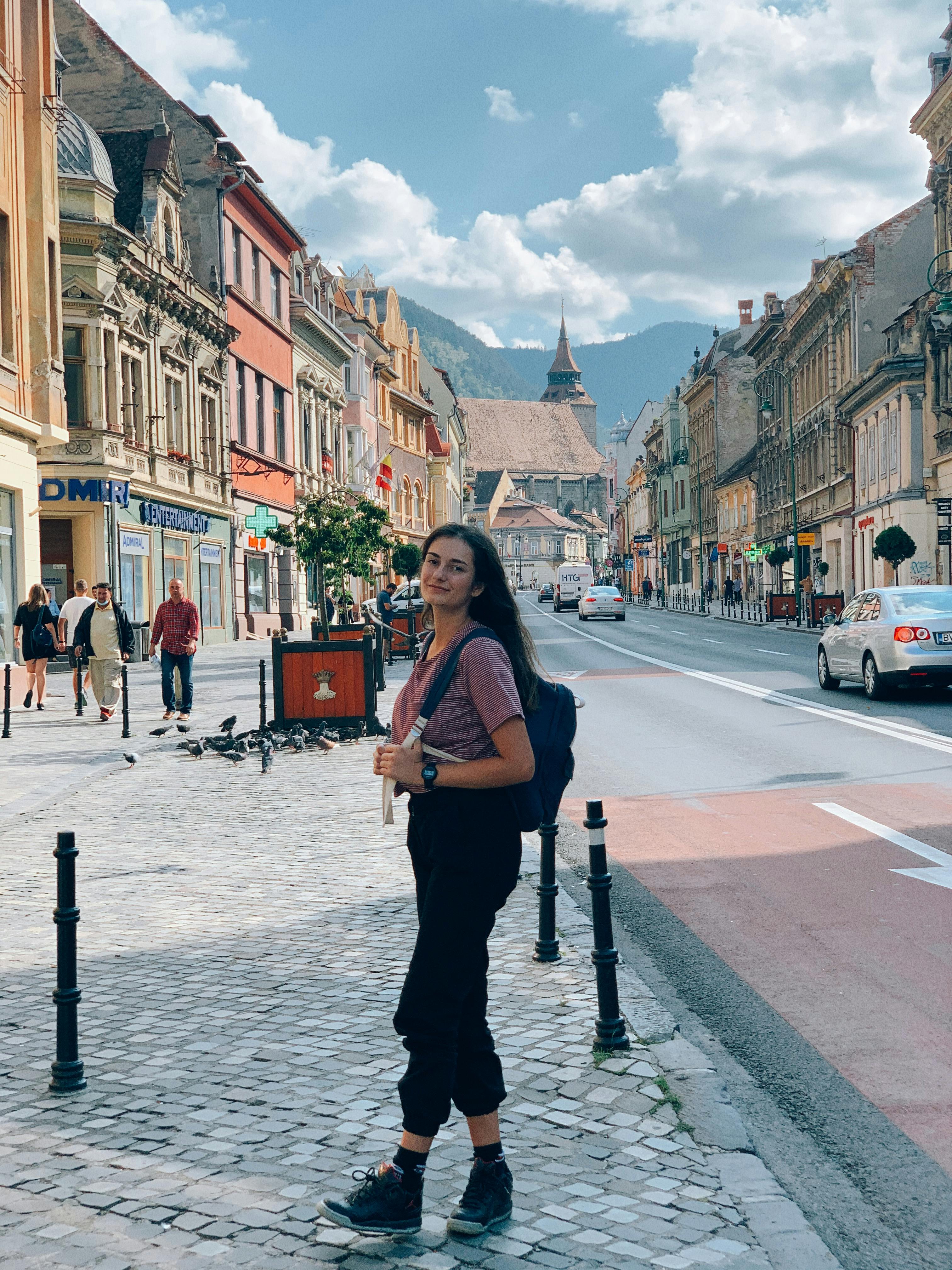 Free Young female tourist walking in old city during excursion on sunny day Stock Photo