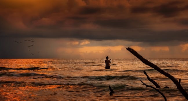 A lone fisherman casts at sunset against a dramatic seascape.