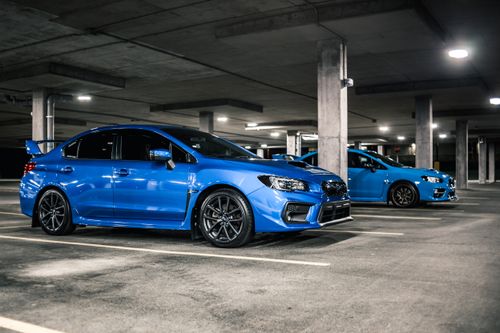 Free Side view of expensive blue cars with black modern disks and spoilers on trunks parked on underground parking lot with columns Stock Photo