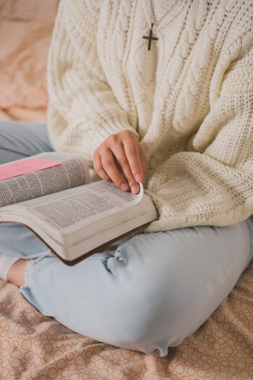 Person in White Knit Sweater Reading Book