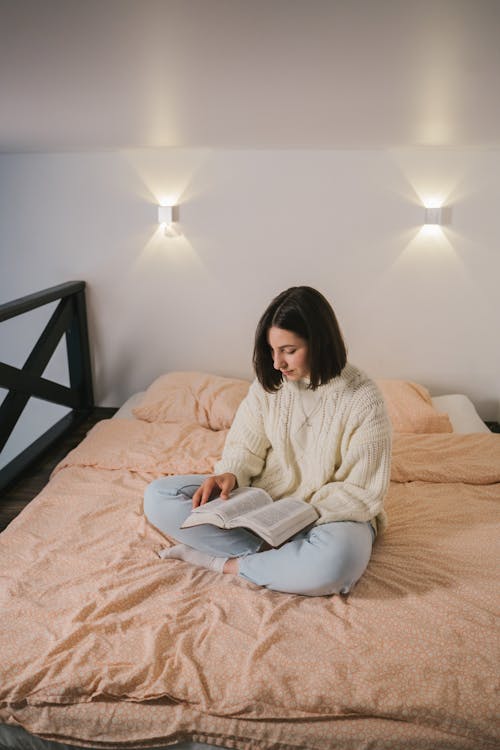 Woman in White Sweater Sitting on Bed