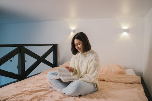 Woman in White Sweater Sitting on Bed Smiling