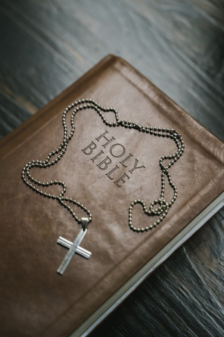 Silver Cross Pendant Necklace On Brown Holy Bible