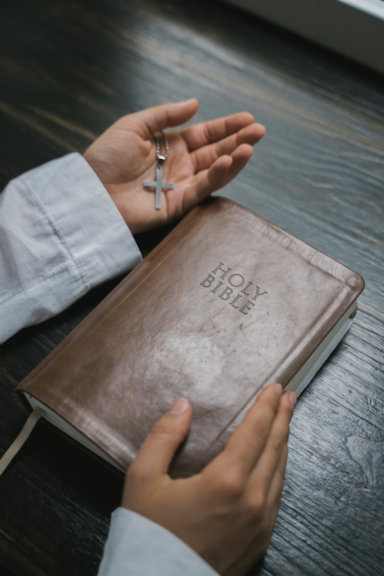 Person Holding A Book And Cross