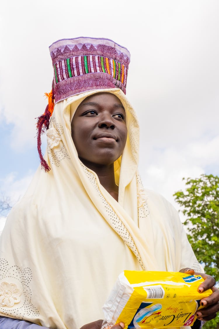 A Woman In Yellow Scarf Holding Pack Of Sanitary Pads