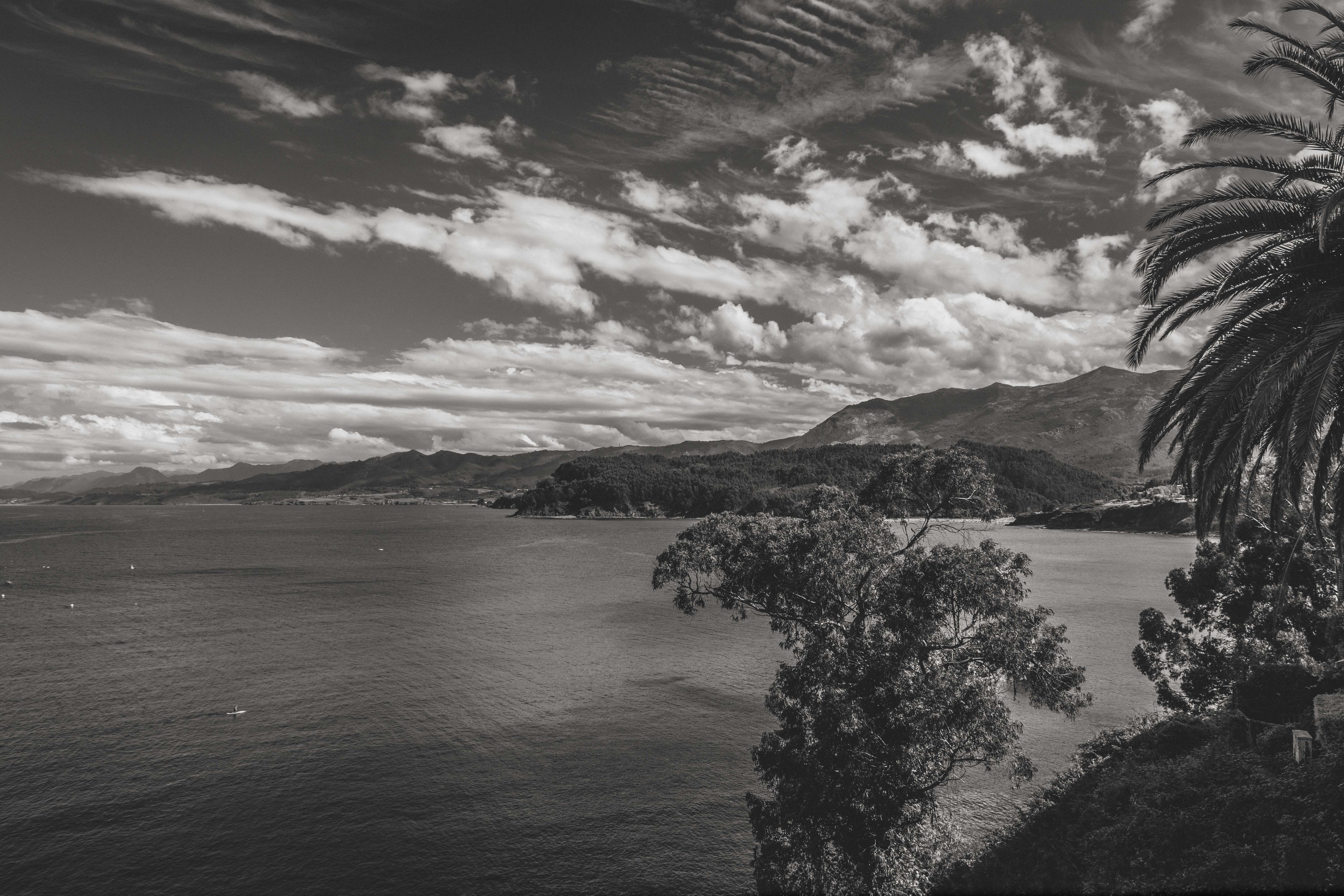 A captivating black and white landscape of Lastres coastline with mountains and the sea under dramatic clouds.