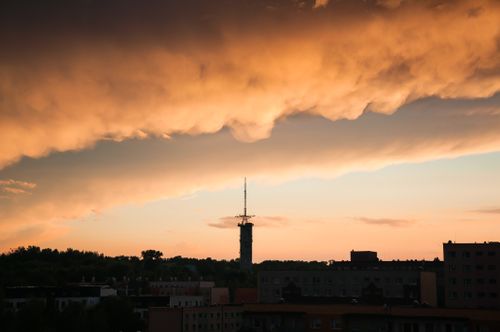 Free Stunning cityscape featuring dark clouds and a prominent tower during an enchanting sunset. Stock Photo