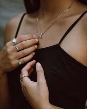 特写镜头聚焦于一位女士的双手，展示了她佩戴的精致银戒指和项链