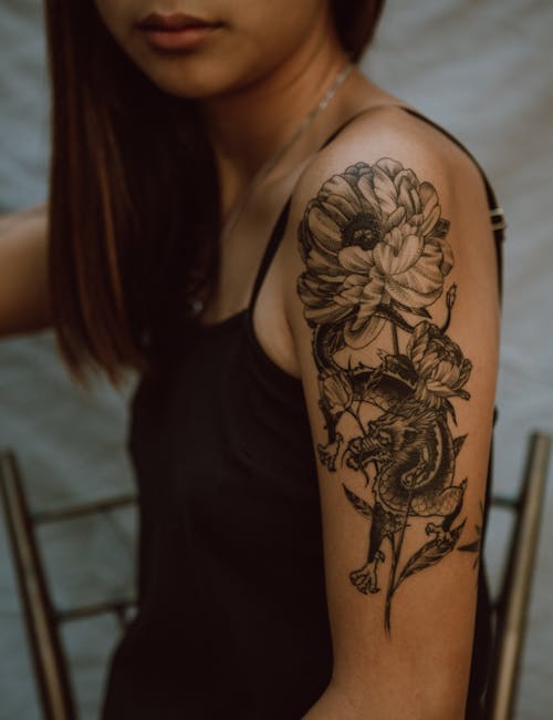 Side view of crop anonymous female with picture of dragon and flower on hand