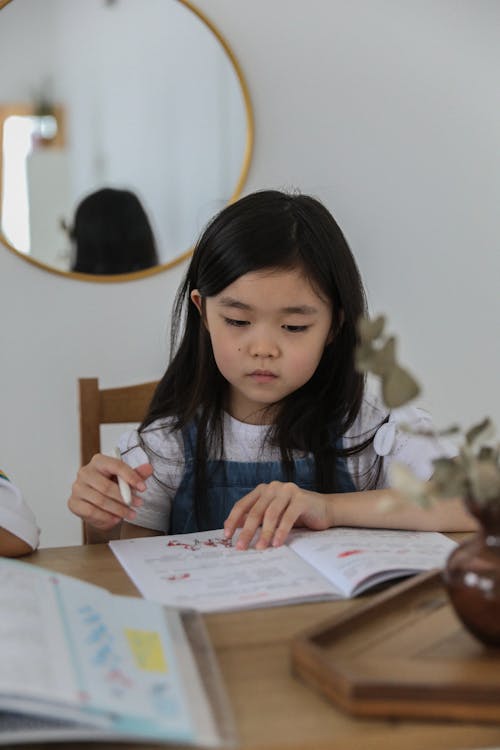 Free Thoughtful Asian girl doing homework Stock Photo