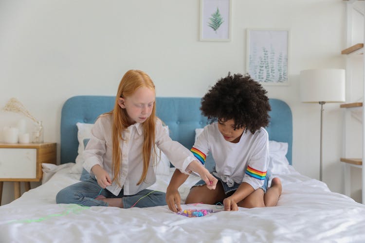 Diverse Best Friends With Beads On Cozy Bed