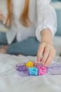 Crop girl taking bright beads from plastic box on bed