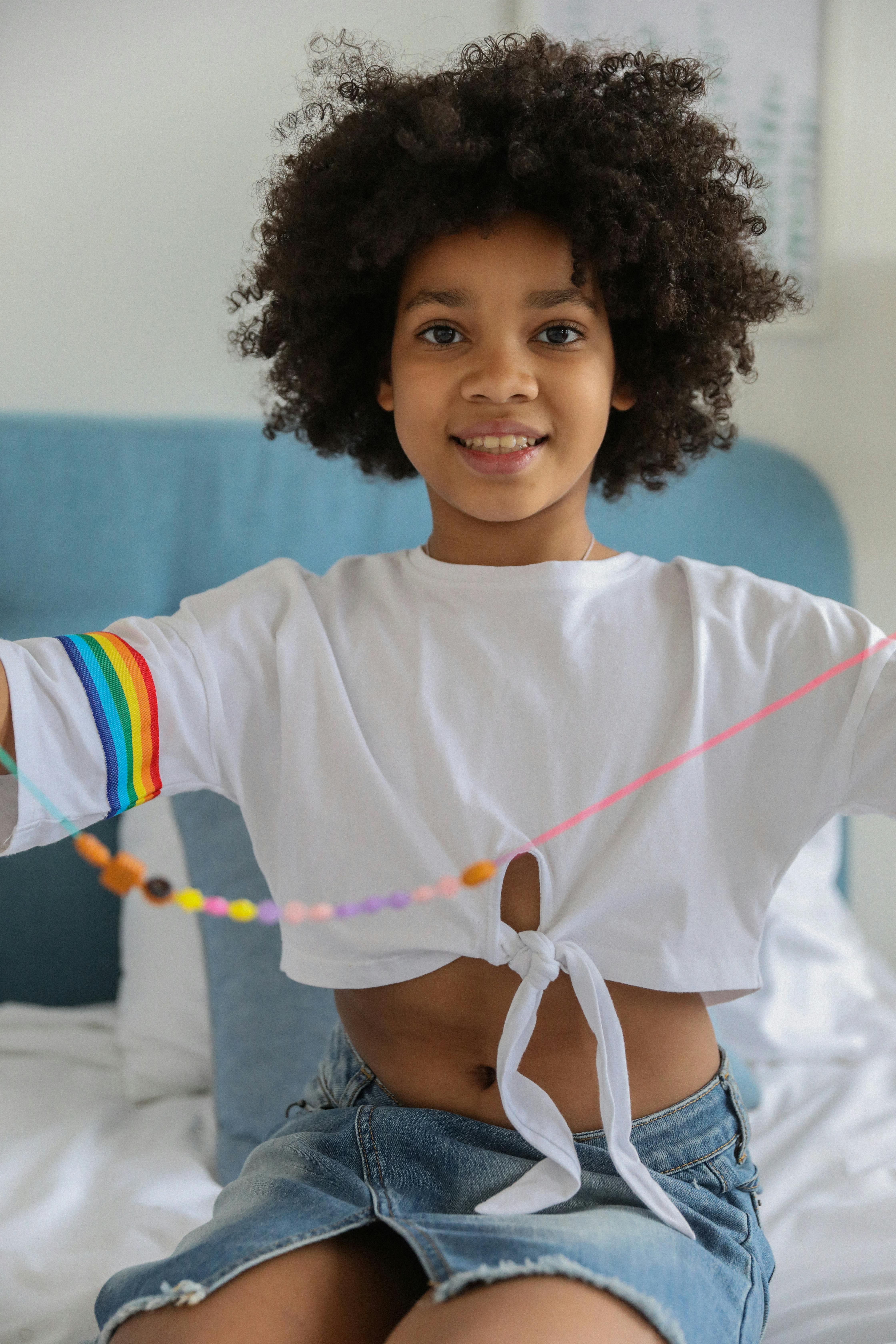 cheerful ethnic girl showing beads on bed