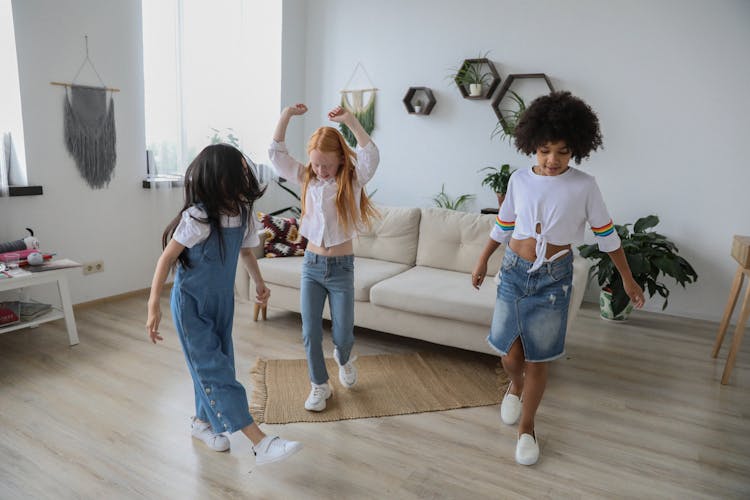 Multiracial Girls With Anonymous Friend Dancing On Floor At Home