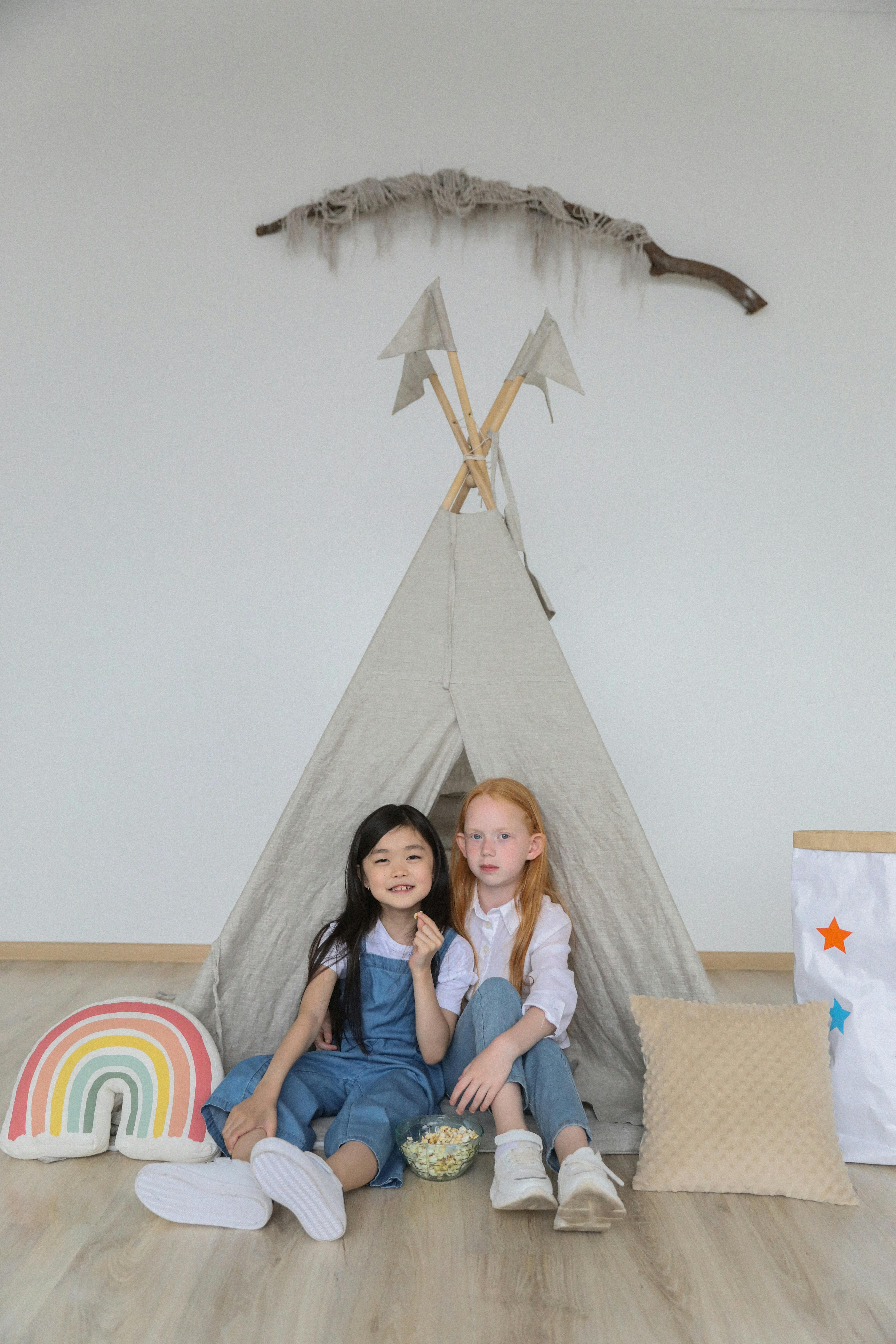 cute little diverse children relaxing on floor near tent at home