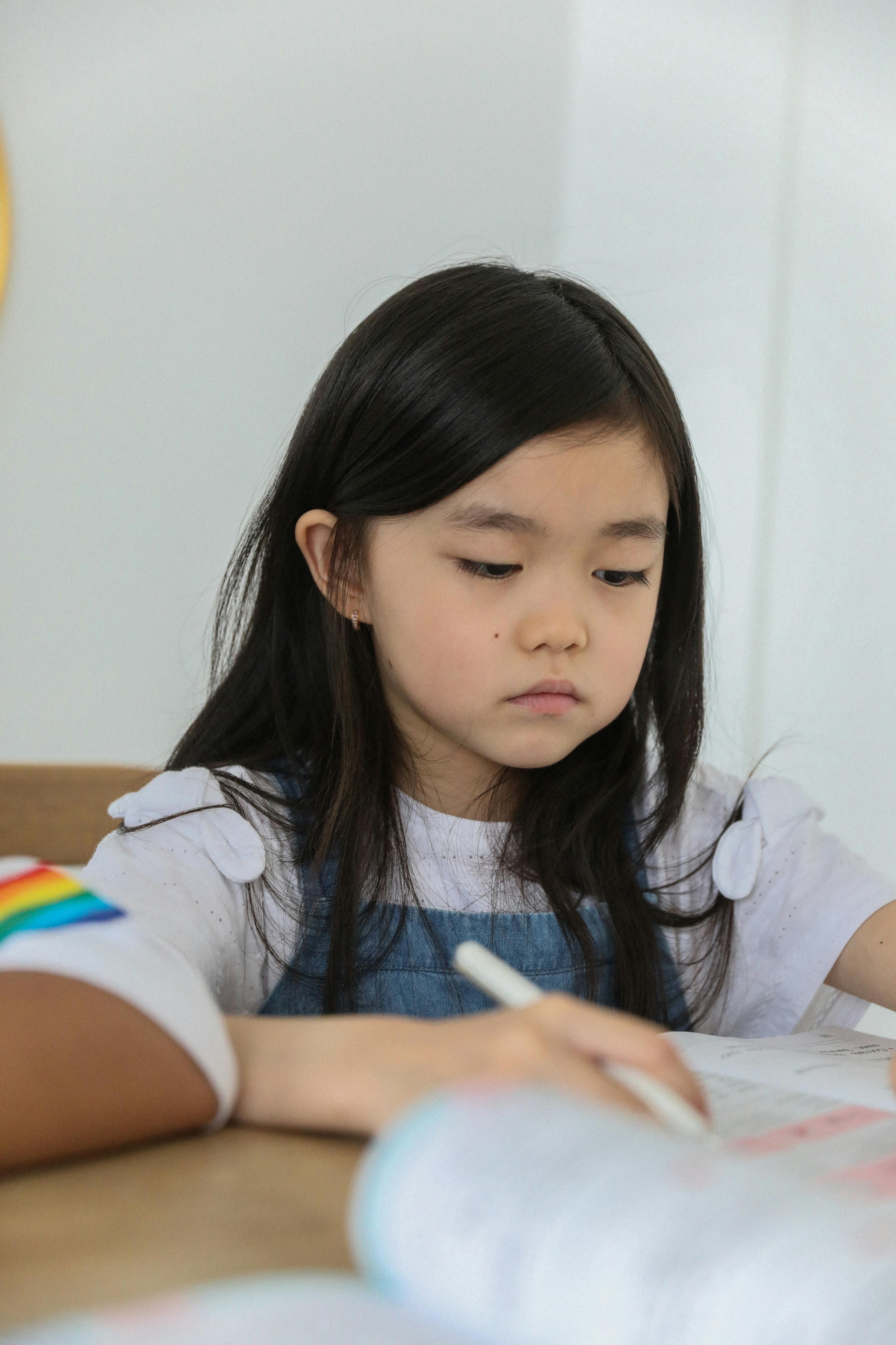 focused ethnic schoolgirl doing studies at table in classroom