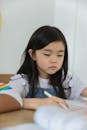 Focused ethnic schoolgirl doing studies at table in classroom