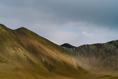 Picturesque view of rocky valley with rough surface located in mountainous area against cloudy sky in nature in highlands on summer day