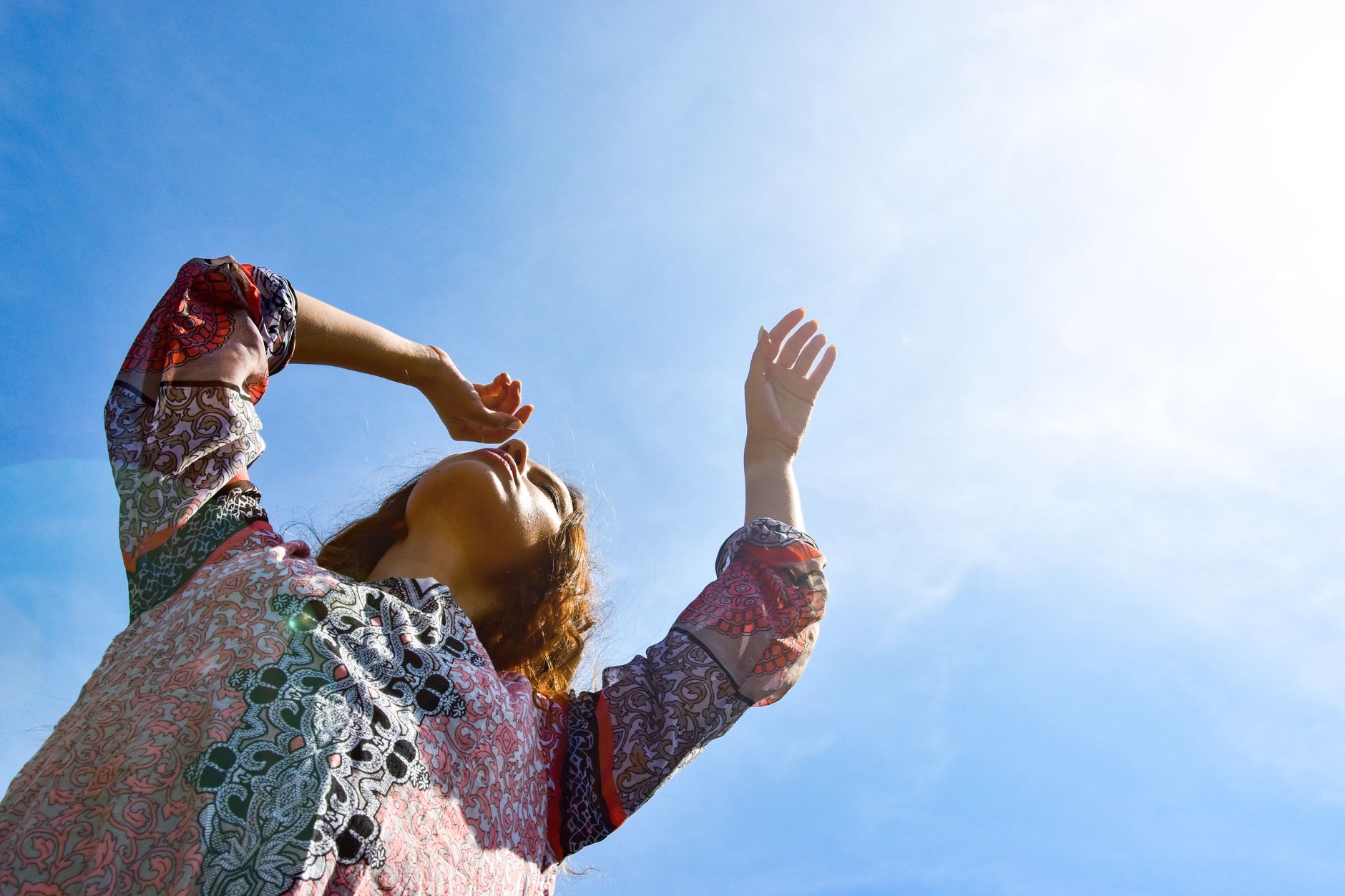vitamin d3 k2 for immune support after covid — Low angle view of a woman with arms raised against a bright sunny sky.
