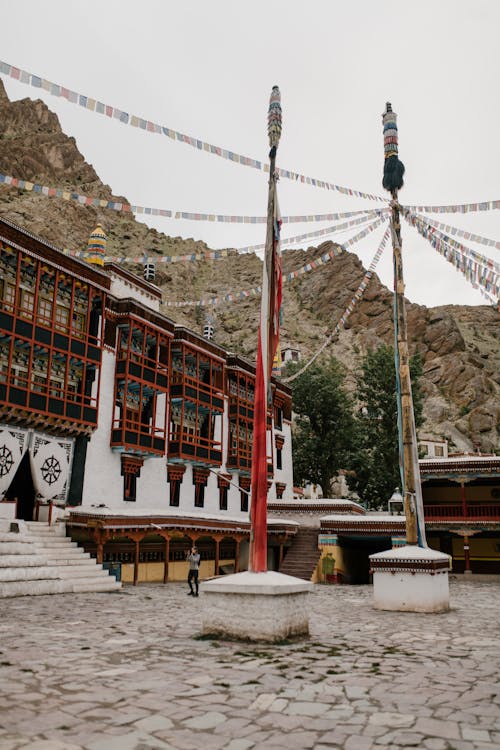 Exterior of Hemis monastery with stair located on pavement with columns with hanging many small flags in mountainous area on street