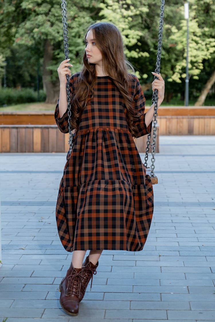 Calm Woman In Loose Dress Sitting On Swing